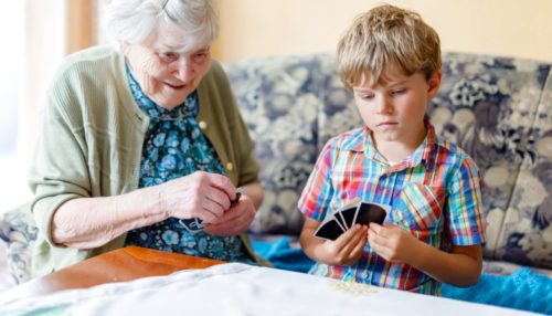 A memory care resident plays cards with her grandson at a care home for dementia