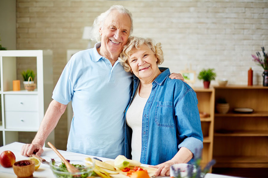 An older adult couple smiling while spending time together cooking