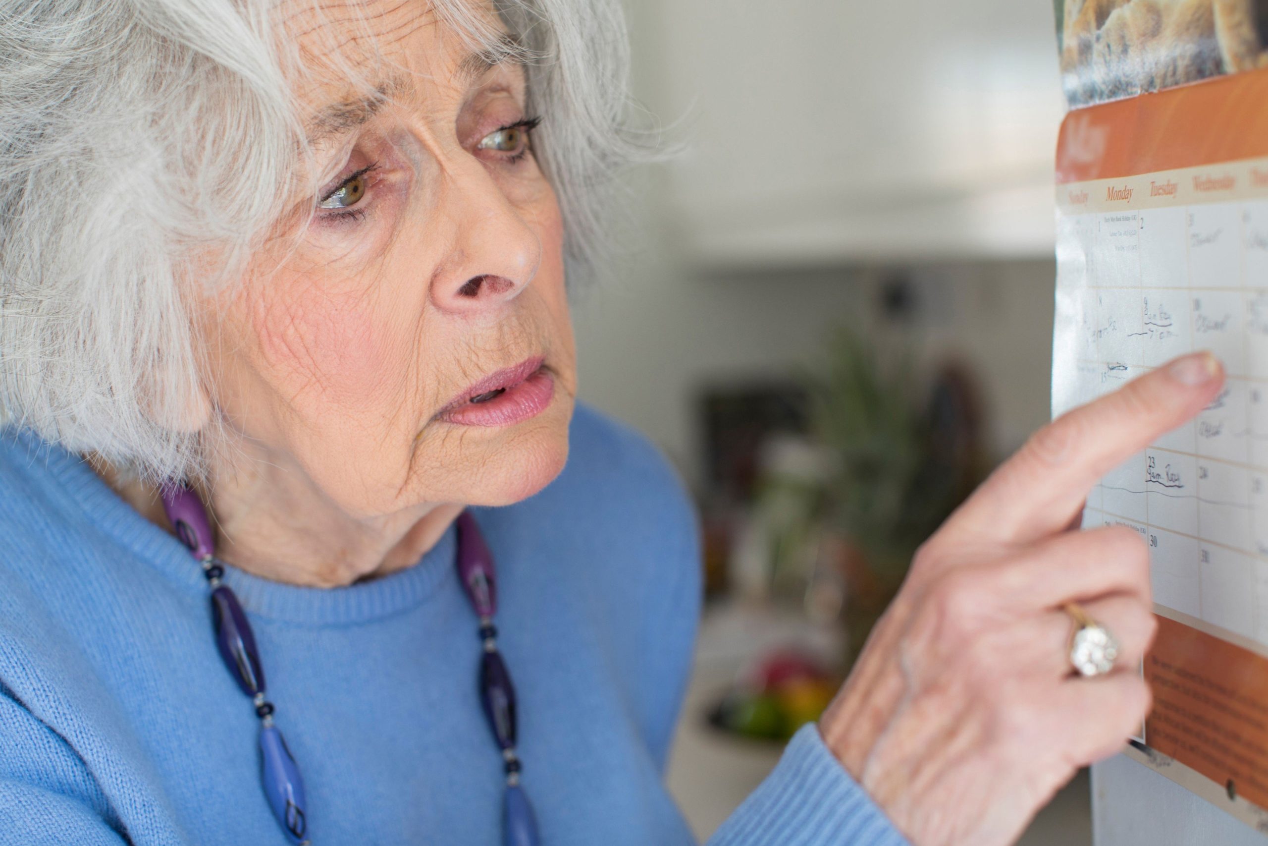 Confused senior woman with alzheimer's looking at the date.