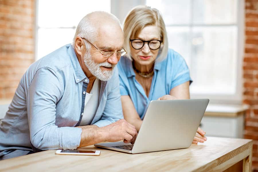 Senior couple scheduling a visit to a memory care facility using their laptop.