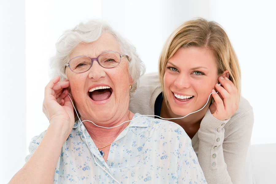 Senior woman and her daughter listening to music together boosting positive mood.