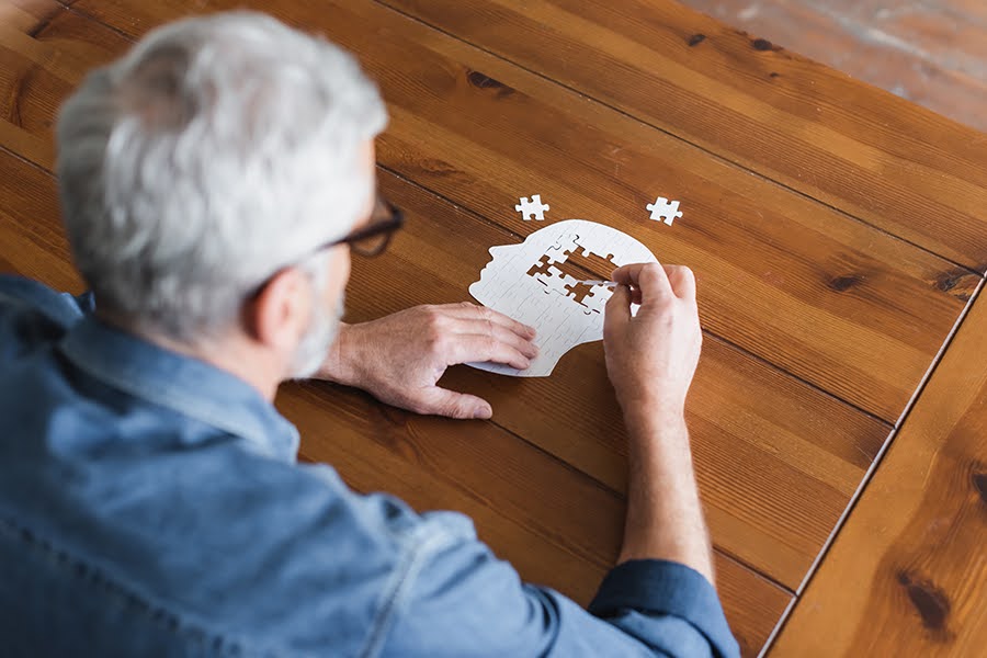 An elderly man with Alzheimer's disease engages in a puzzle, benefiting from memory care in Maryland. Senior care in Montgomery County MD