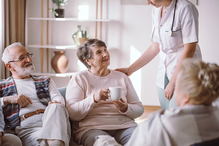 A group of seniors with a nurse in a lounge discussing dementia and Alzheimer's care.