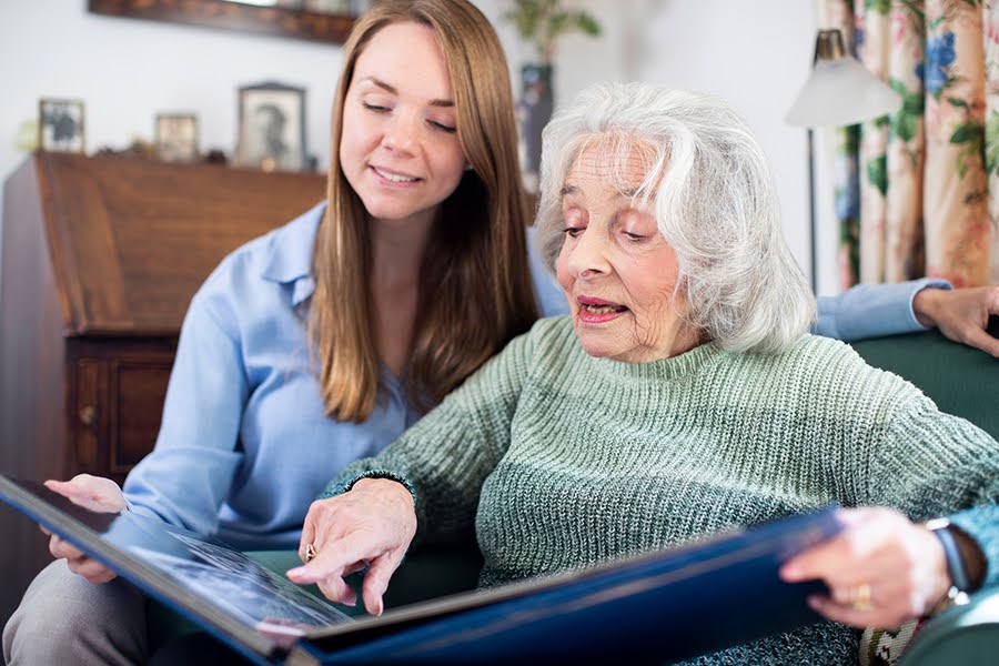 A senior woman with a caregiver reviewing a photo album in a memory care home near Dupont Circle