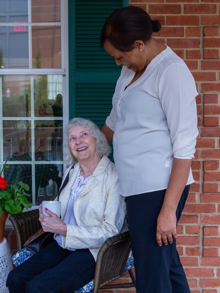 Caregiver smiling with senior on porch, showing supportive memory support near Aspen Hill, MD. Caregiver smiling with senior on porch, showing supportive memory support near Aspen Hill, MD.