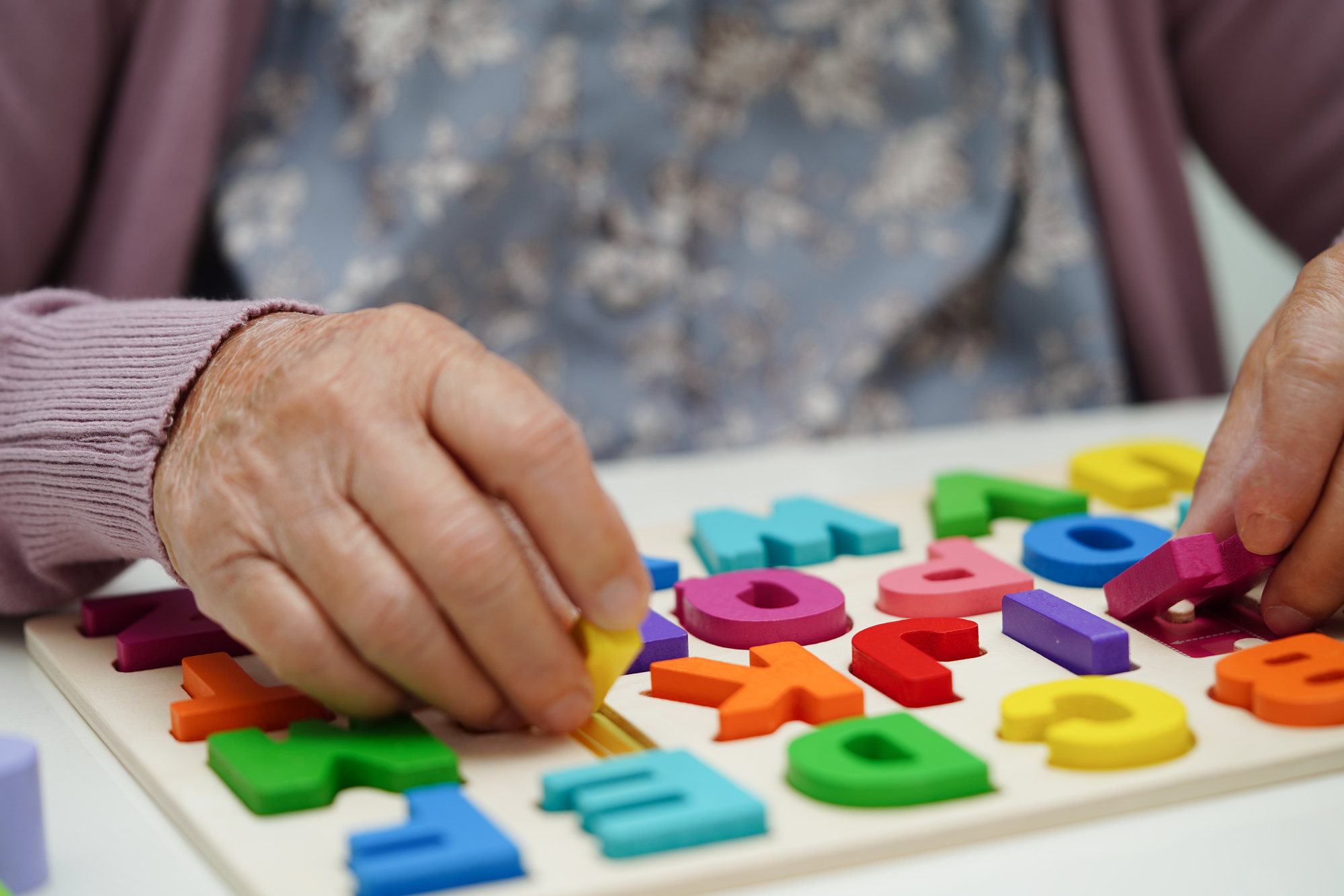 Asian elderly woman playing puzzles game to practice brain train Planned social activities 7 days a week, such as card games or art lessons