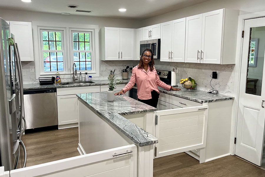 Caregiver in a secure, homelike kitchen designed for senior dementia assisted living, with safety gates and clean space.