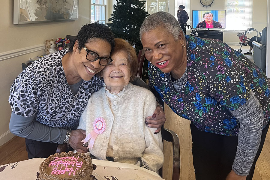 Caregivers celebrate a resident's birthday with cake in a warm, supportive dementia long term care setting.