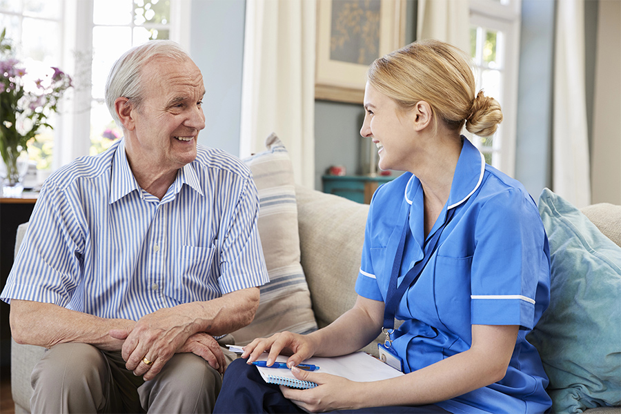 Compassionate caregiver assisting elderly person with a gentle, supportive interaction in a warm environment.