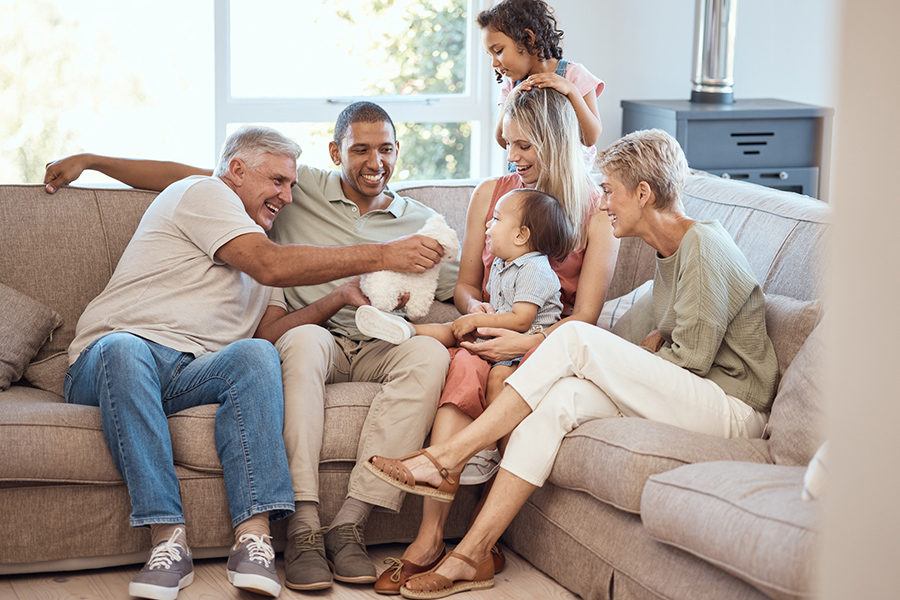 Family sitting together on a couch, smiling and talking, representing questions to ask aging parents conversations