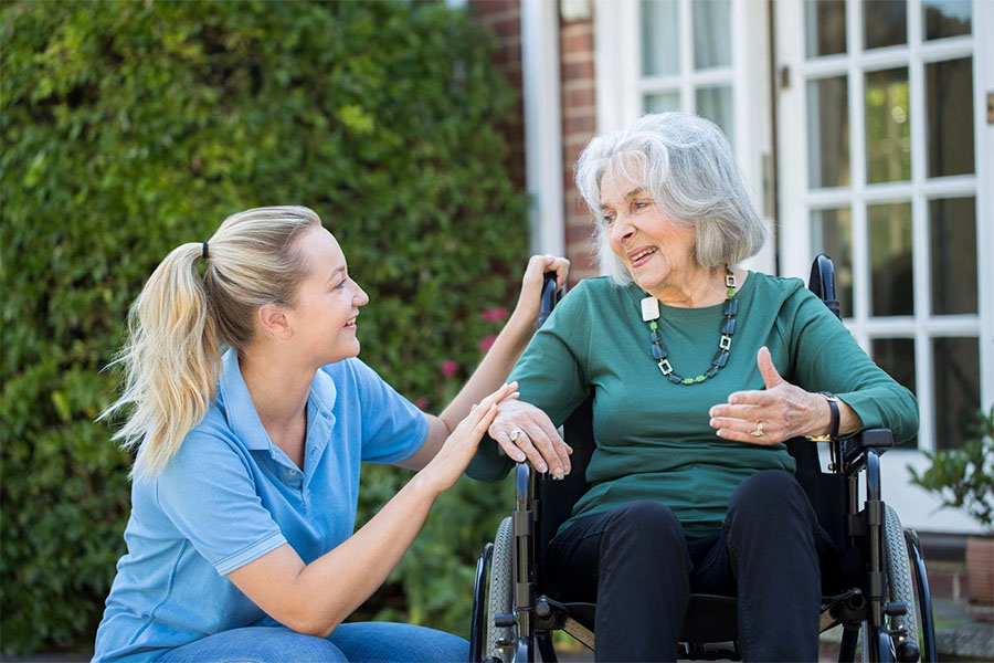 Caregiver supporting an elderly woman in a wheelchair, showing compassionate care during the progress of dementia Caregiver supporting an elderly woman in a wheelchair, showing compassionate care during the progress of dementia