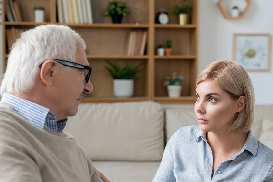 Older man and younger woman talking seriously at home, illustrating a discussion about dementia aggression Older man and younger woman talking seriously at home, illustrating a discussion about dementia aggression