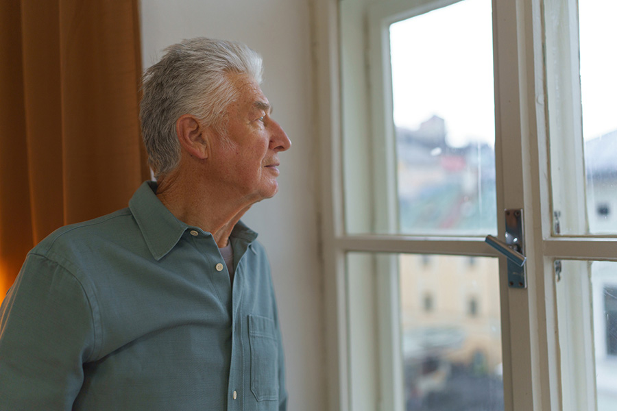An elderly man looking out a window, representing how reduced visual acuity is one of several risk factors that may be linked to developing dementia An elderly man looking out a window, representing how reduced visual acuity is one of several risk factors that may be linked to developing dementia