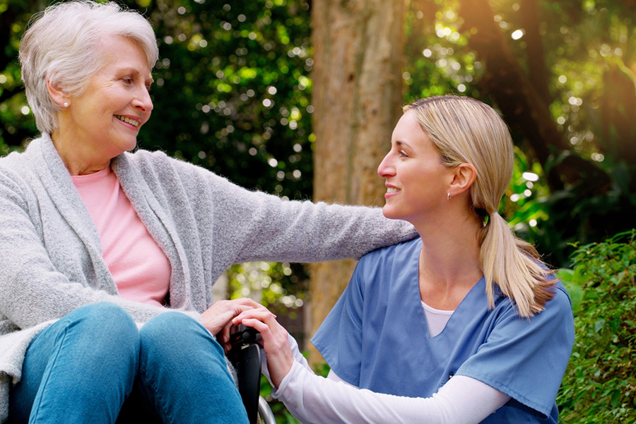 A smiling caregiver supports a senior in a wheelchair, illustrating Memory Care Near Montgomery Village, MD