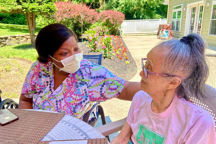 Caregiver and resident sitting outdoors at a small house model dementia care home.