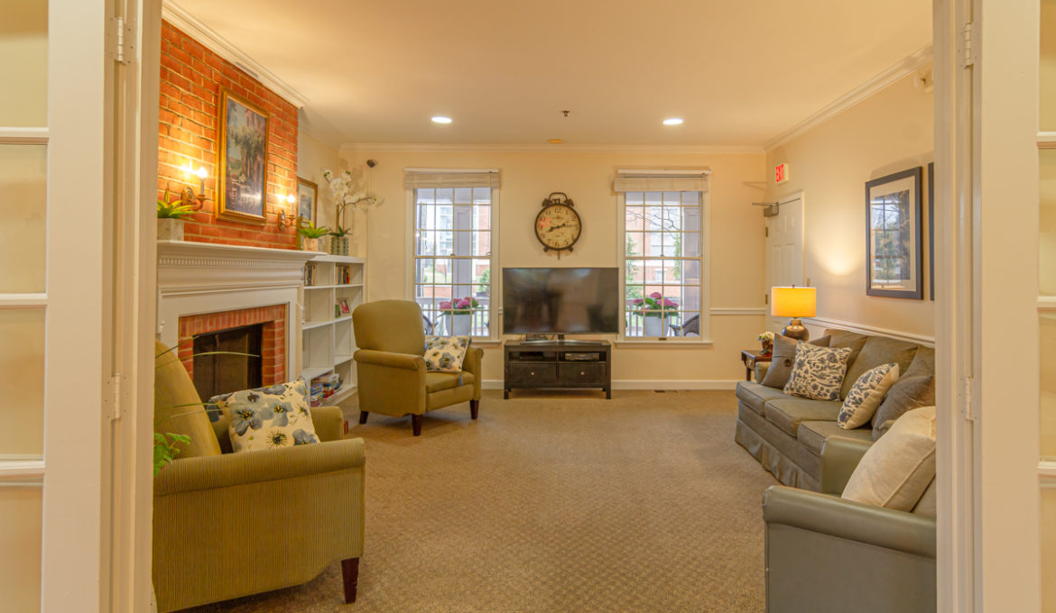 Home-like dementia care living room setting at a Cedar Creek residential home featuring a fireplace, comfortable seating, and a warm atmosphere
