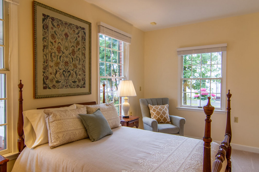 Cozy private resident bedroom at Cedar Creek Memory Care featuring a wooden four-poster bed and warm, homelike decor.