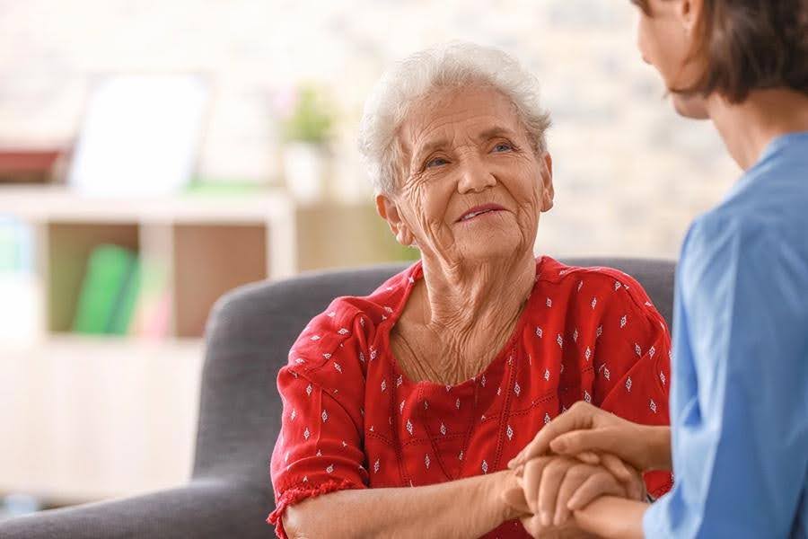 Caregiver making gentle eye contact and holding hands with a senior resident during active listening
