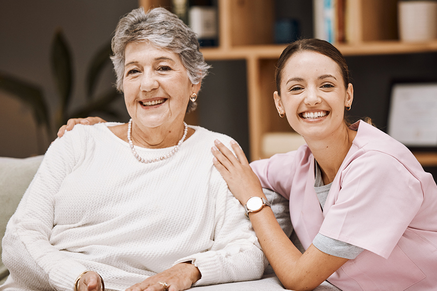Specialized dementia caregiver in scrubs smiling alongside a senior memory care resident.