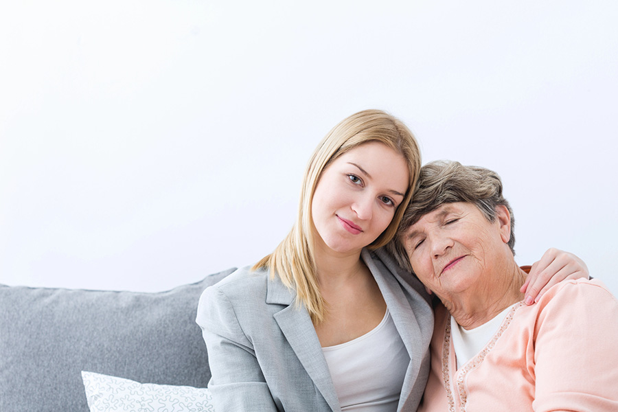 Thoughtful adult daughter contemplating senior memory care options and caregiver stress.