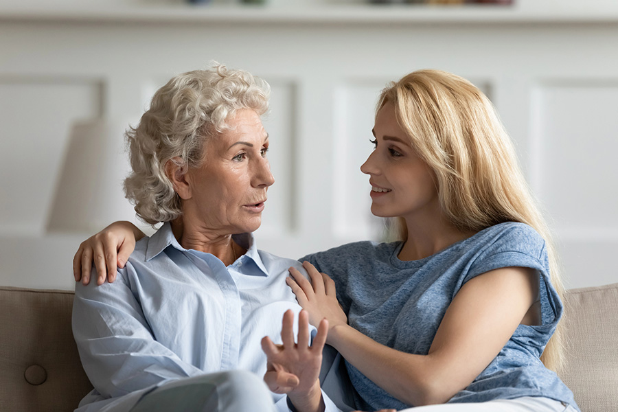 A family caregiver using calm reassurance and gentle eye contact to soothe a loved one experiencing dementia sundowning symptoms at home. A family caregiver using calm reassurance and gentle eye contact to soothe a loved one experiencing dementia sundowning symptoms at home.